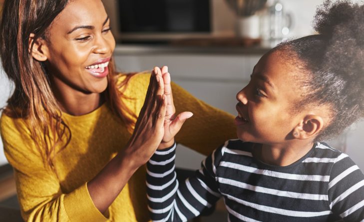 Black mother and child high five in kitchen home