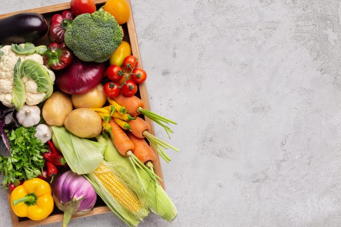 Fresh organic vegetables in wooden box on gray