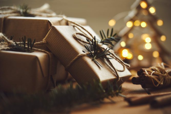 Christmas gifts on wooden table with lights in background