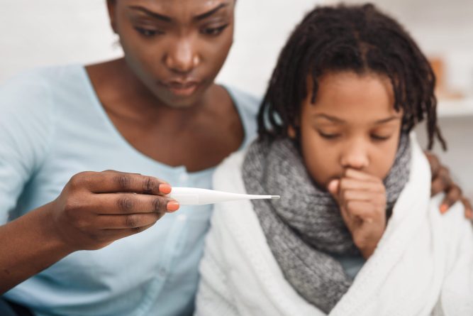 Cold Symptoms. Worried black mother looking at thermometer, ill daughter coughing. Selective focus