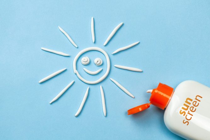 Sunscreen. Cream in the form of sun on blue background with white tube.